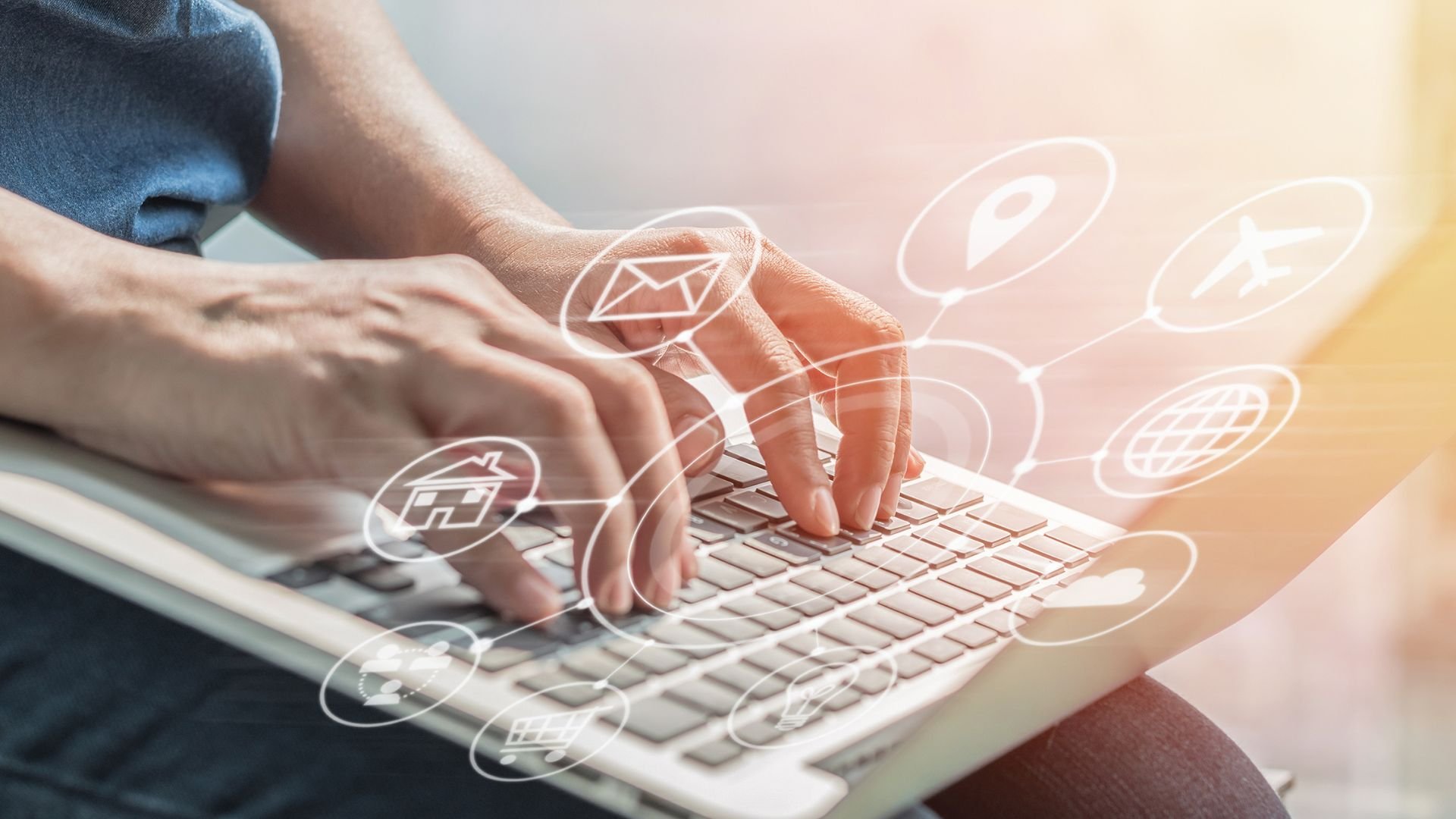 Hands typing on laptop with digital communication icons floating around